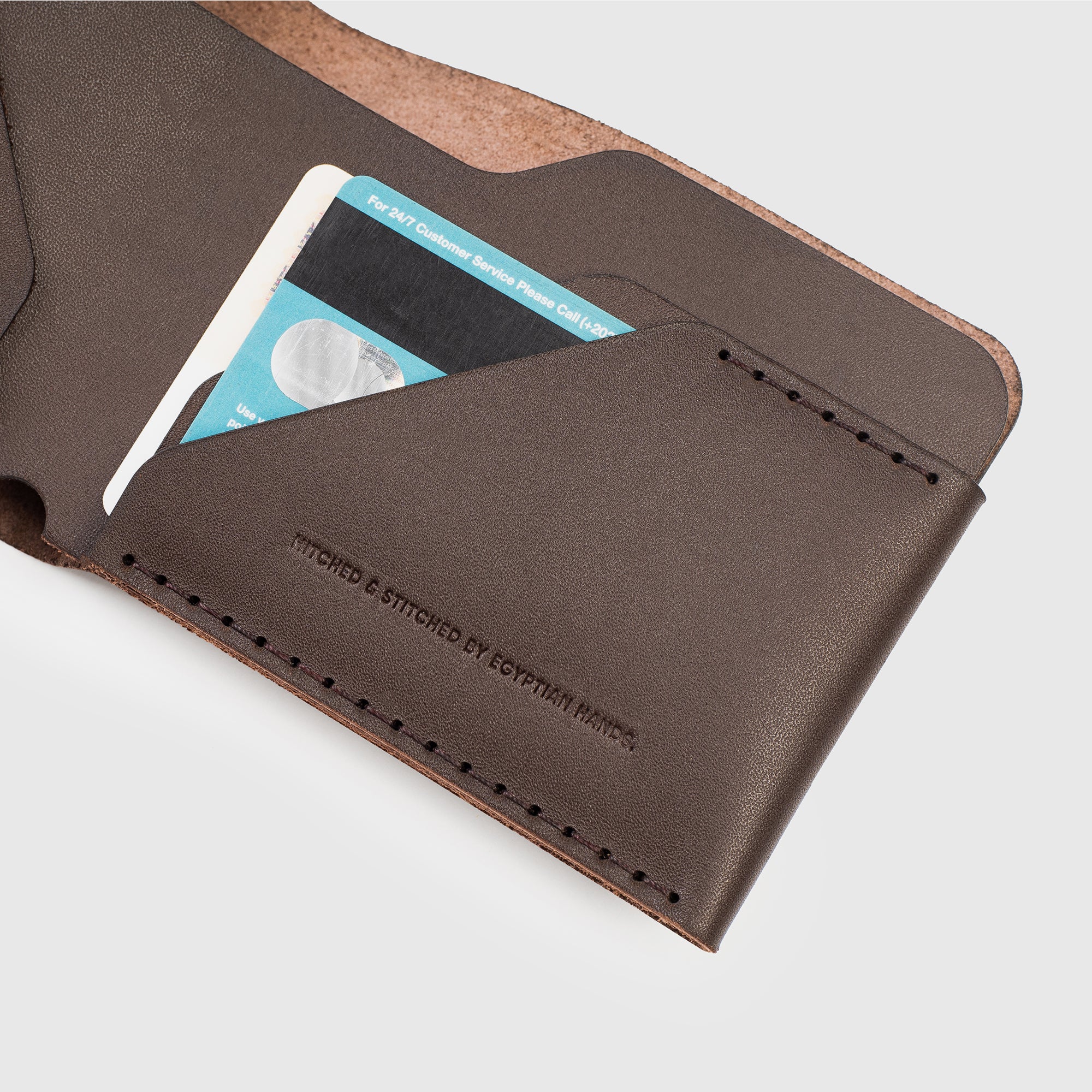 Brown leather bifold wallet with a credit card partially visible, detailed stitching on the edge.