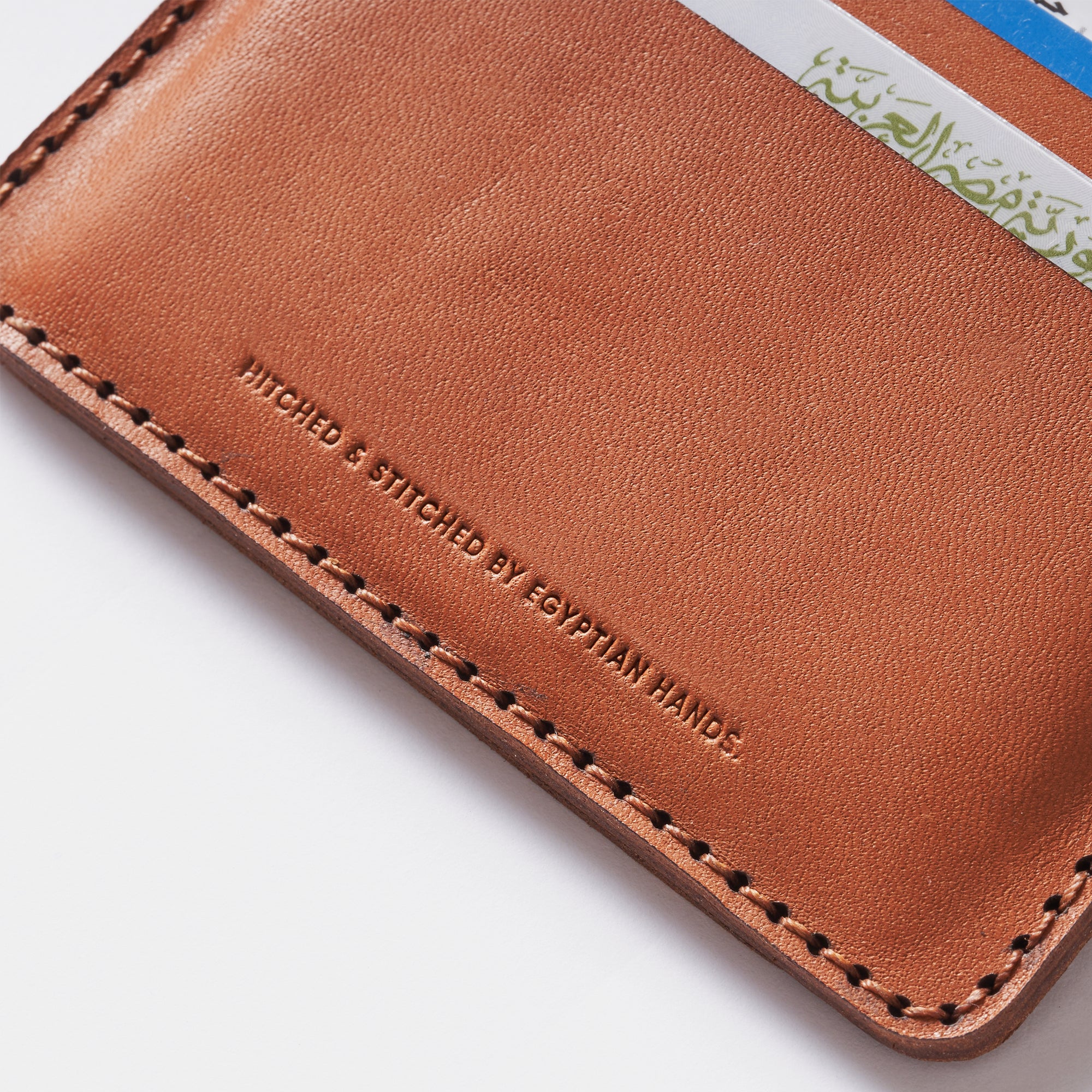 Brown leather bifold wallet with embossed text and visible stitching, partially filled with cards.