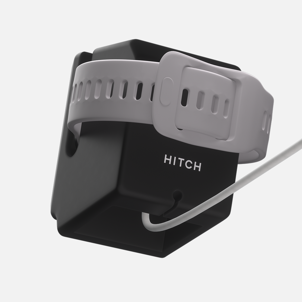 Black Hitch Macintosh Apple watch stand with a black and gray wristband labeled HITCH," white cable visible.