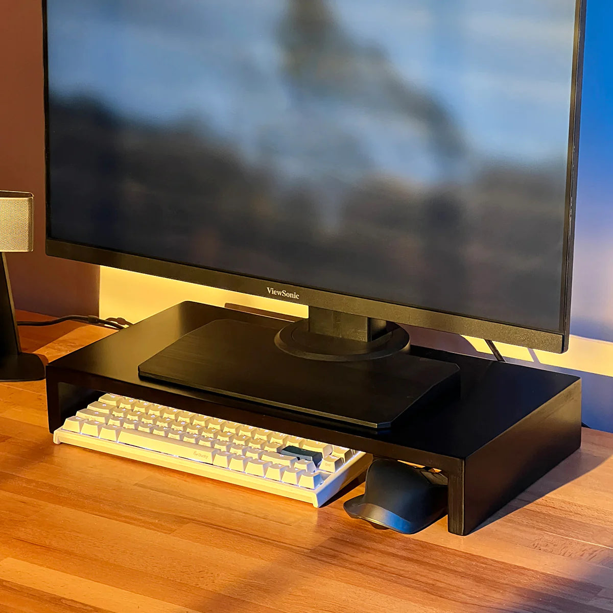Modern stand riser by woodsy with monitor, mechanical keyboard and mouse on wooden desk.