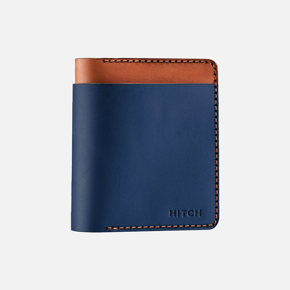 Blue and brown leather bifold wallet with stitched detailing and logo, isolated on white background.