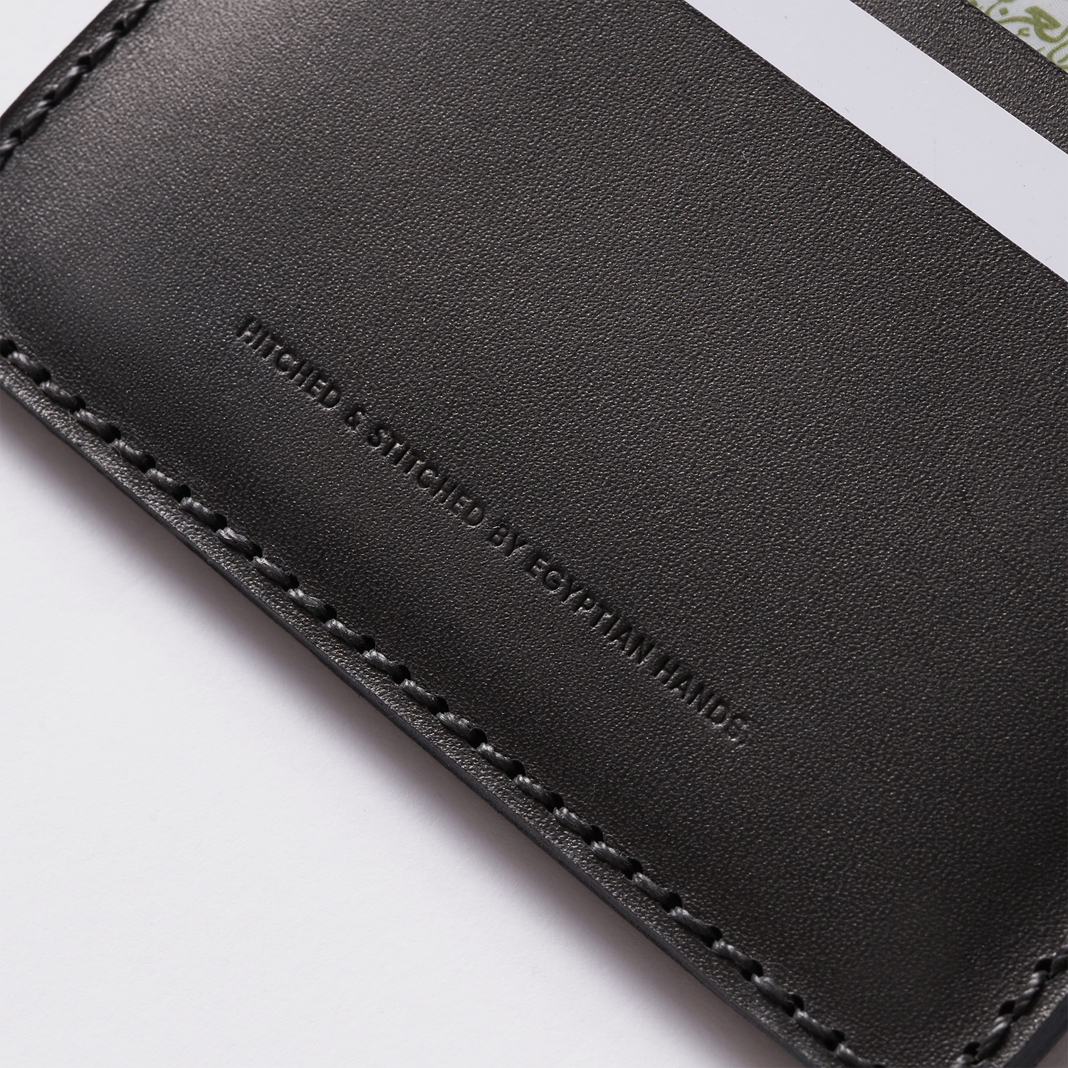 Close-up of a black leather bifold wallet with intricate stitching and embossed branding text."