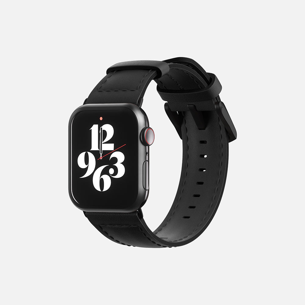 Front view of an Apple smartwatch with stylish numeral face design and black leather strap on white background.