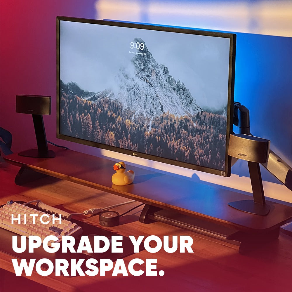 Modern workspace with monitor on desk, ambient lighting, and text "Hitch upgrade your workspace."