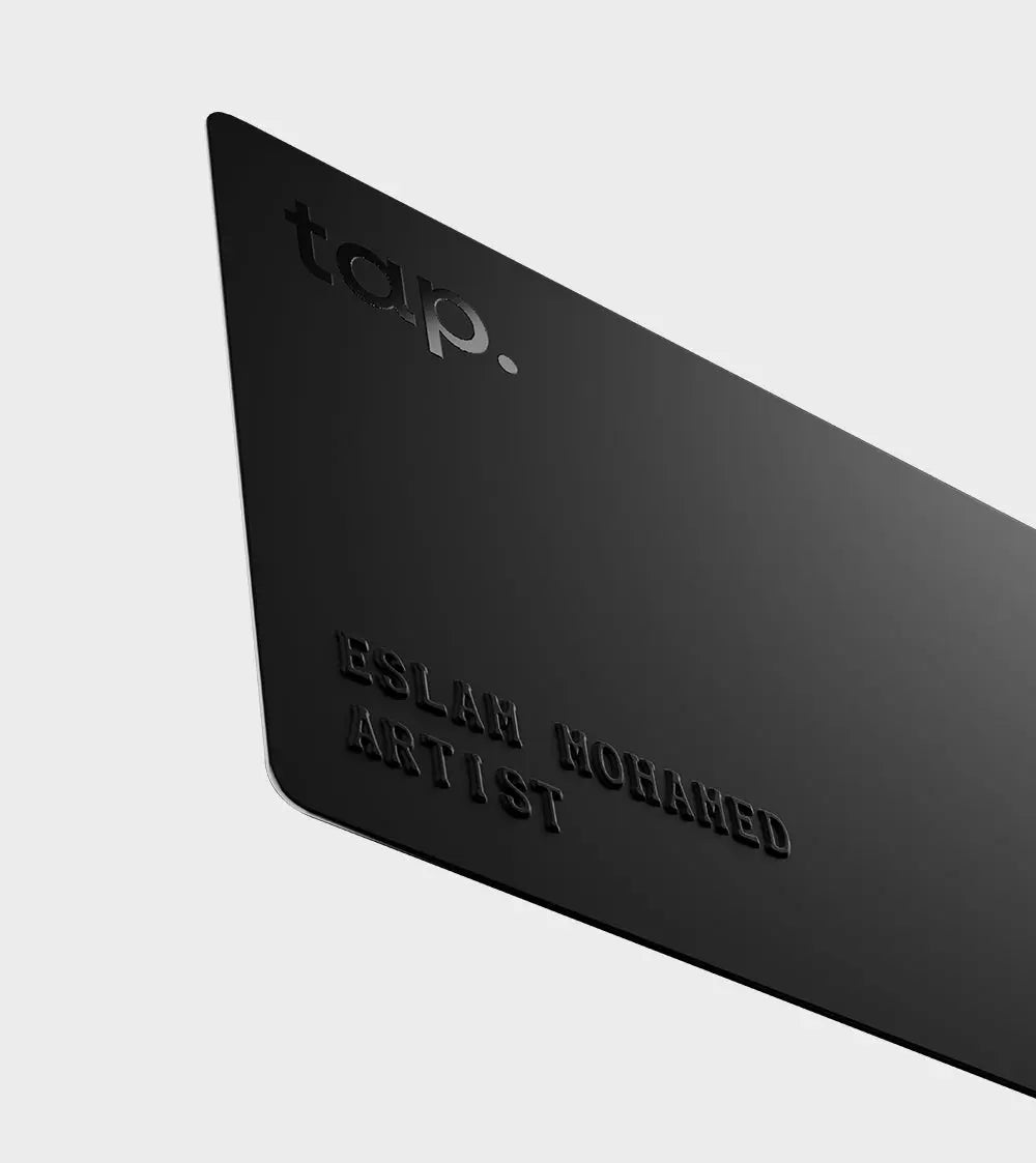 Black NFC business card with embossed text ESLAM MOHAMED ARTIST" and stylized "tap." logo on a dark background.