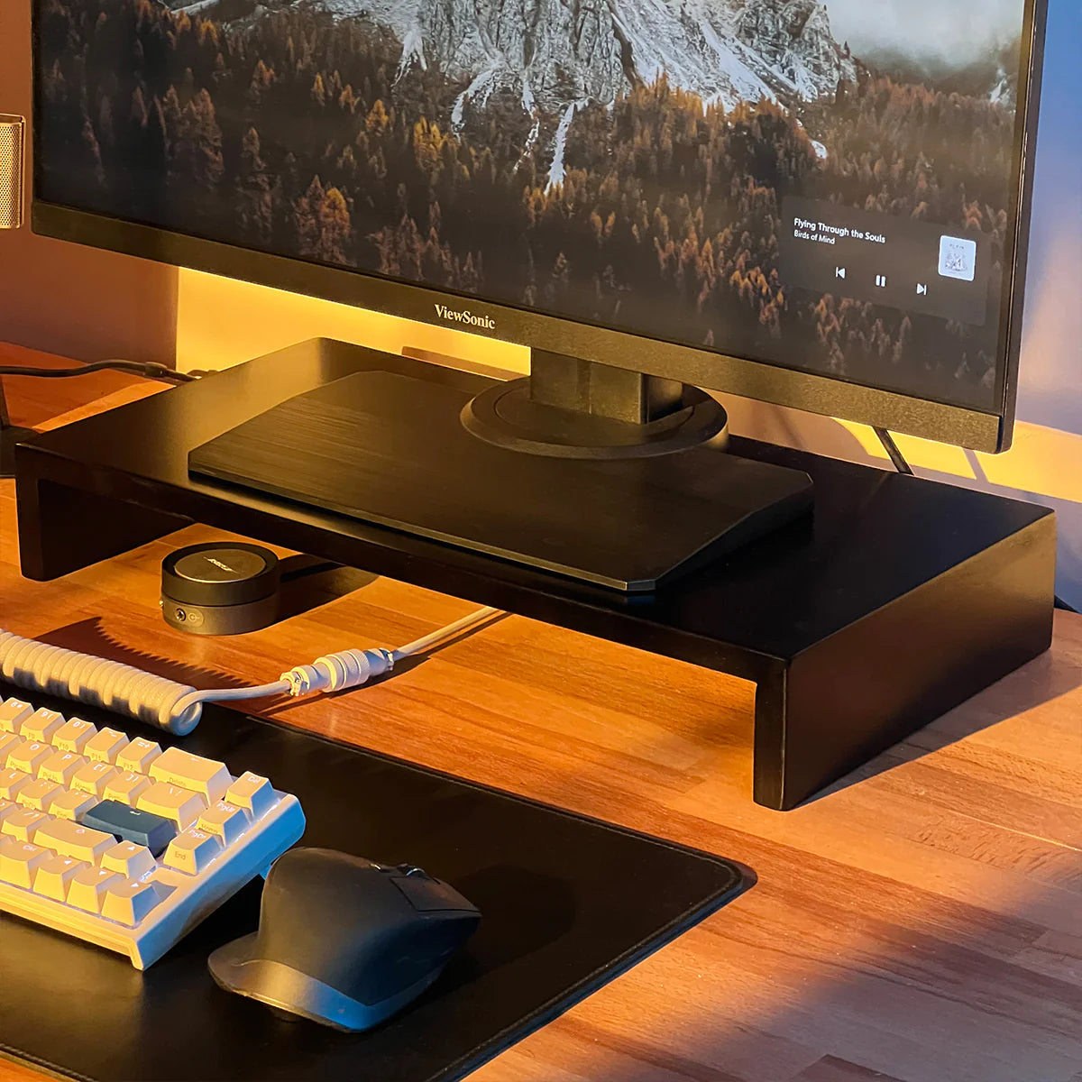 Modern stand riser by woodsy with monitor, ergonomic keyboard, and sleek mouse on wood desk.