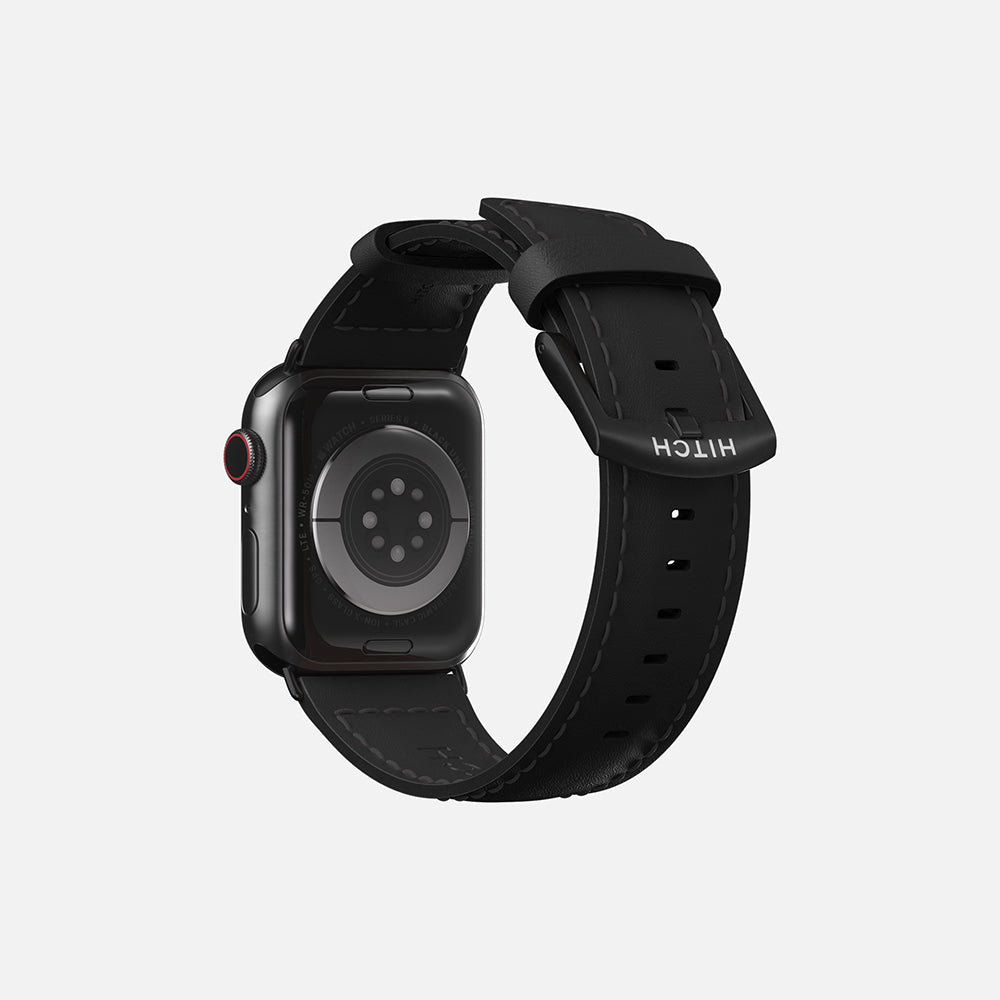 Rear view of an Apple smartwatch with red detail, black leather strap, isolated on a gray background.