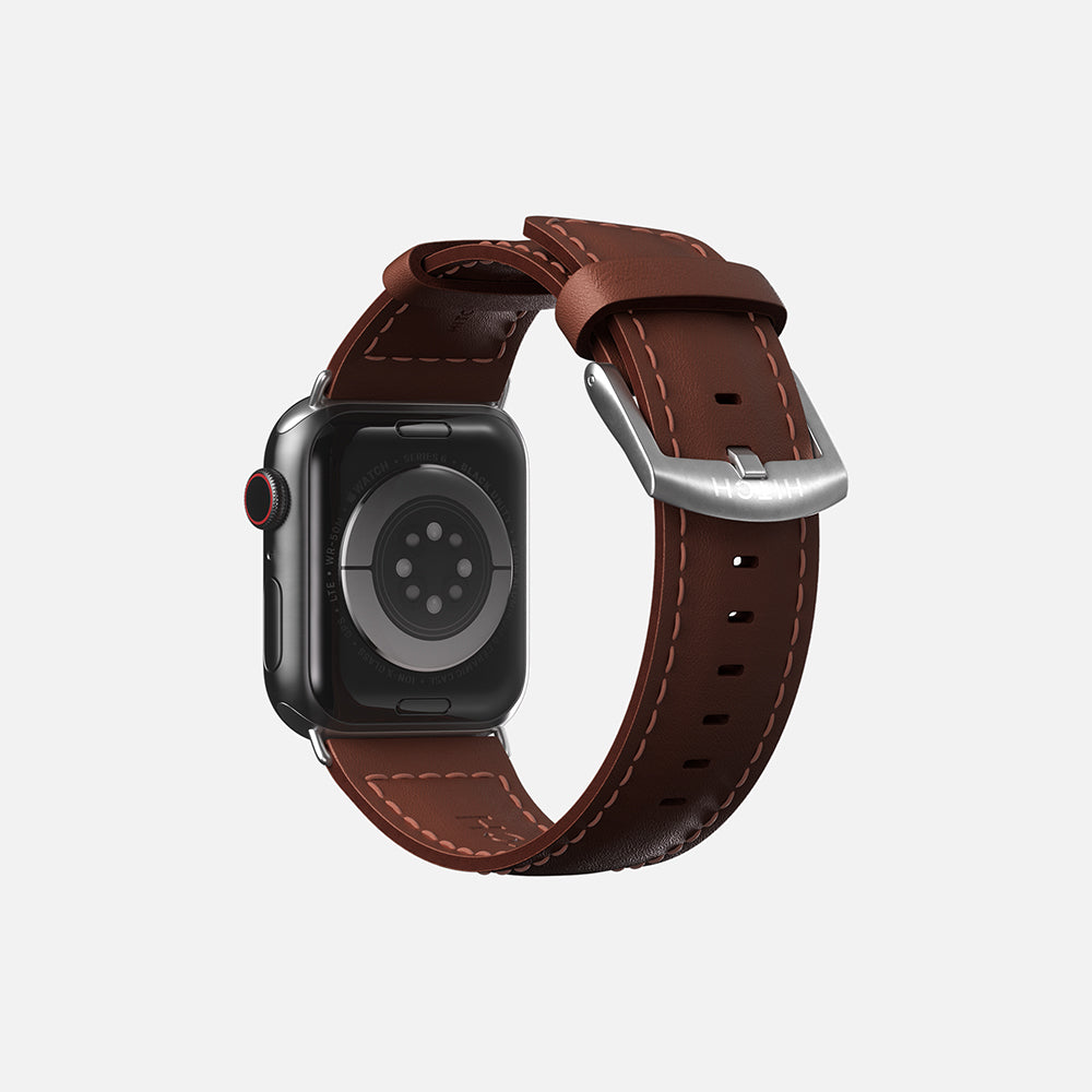 Rear view of an Apple Smartwatch with brown leather strap and digital crown on white background."