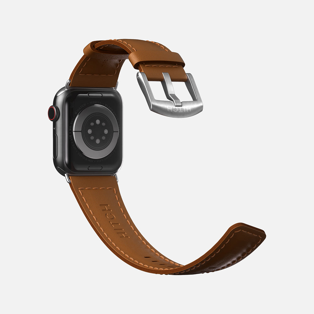 Apple Smartwatch with brown leather strap and silver buckle on a white background.