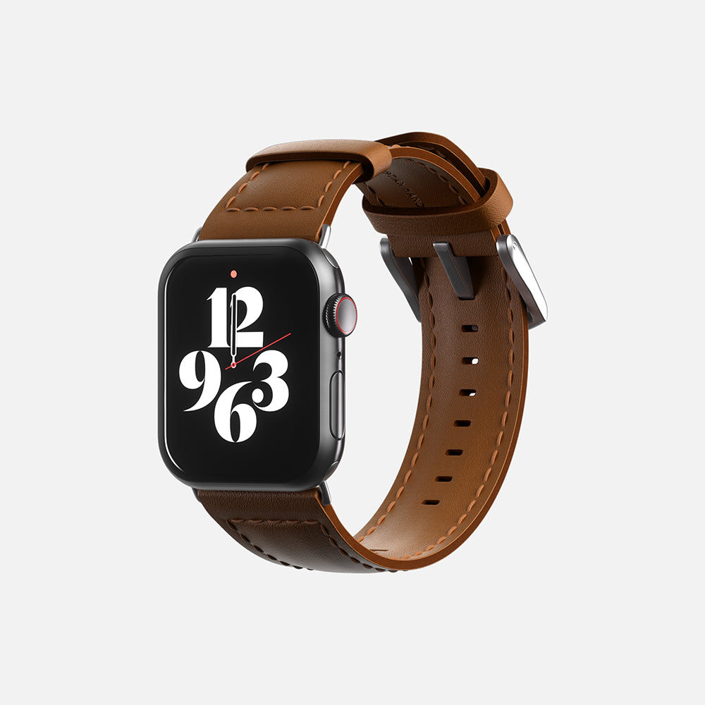 Front view of an elegant Apple smartwatch with brown leather strap and digital clock face display on white background.
