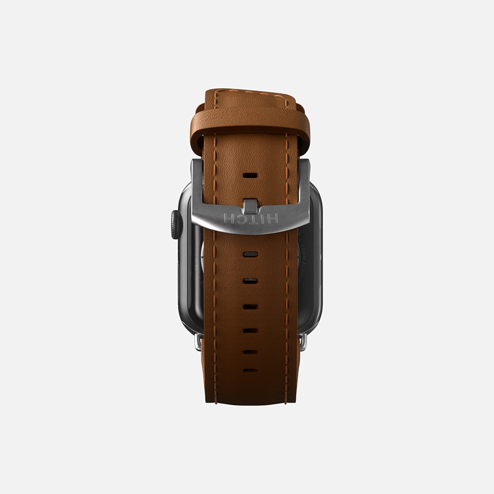 Elegant brown leather Apple smartwatch strap with metal buckle on a white background."