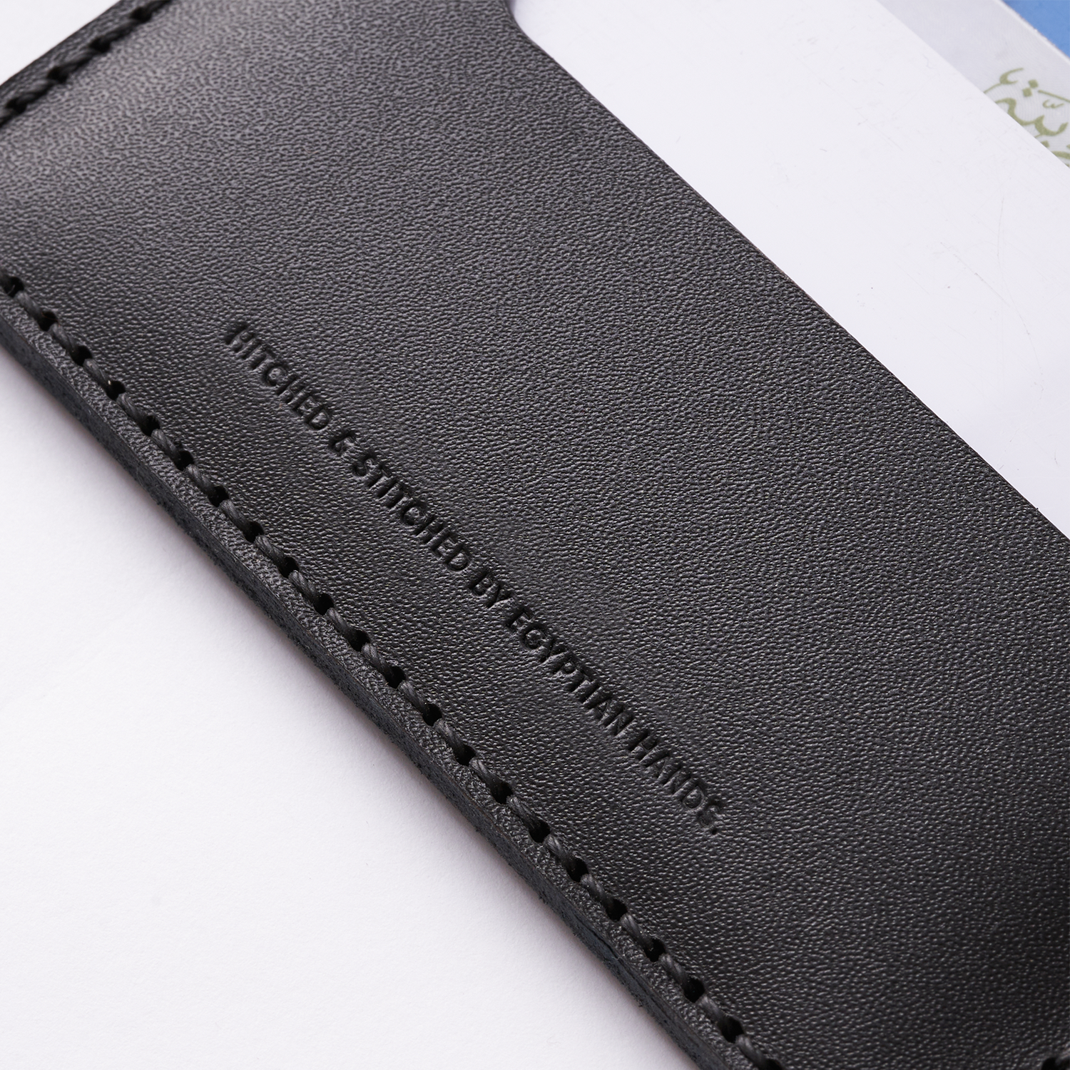 Black leather bifold wallet with stitched detailing, partially showing brand logo.